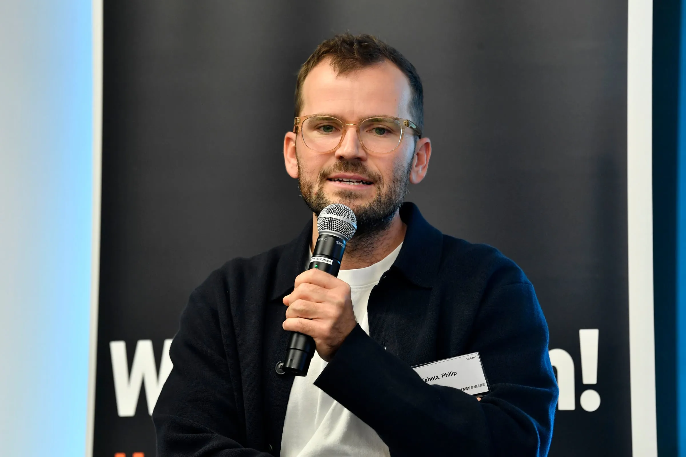 Philip Kehela mit Mikrofon auf der Bühne der Amazon KMU Connect Süddeutschland